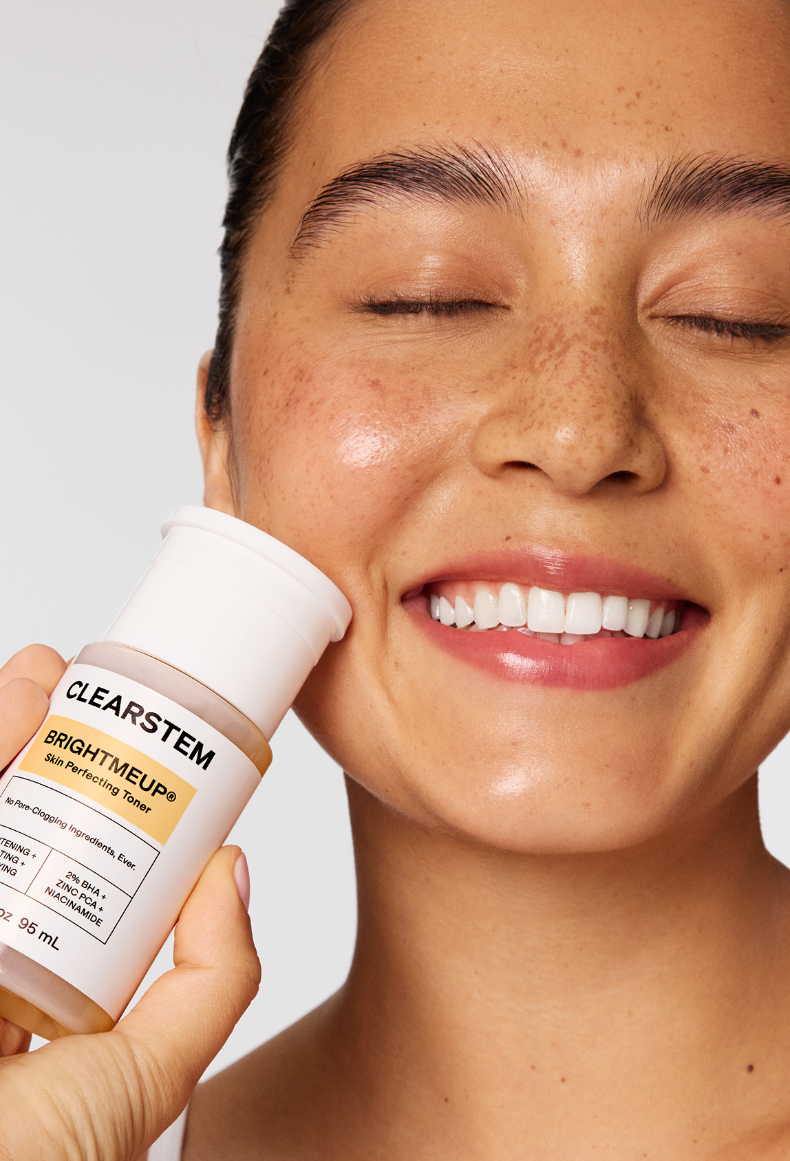 Smiling woman holding a BRIGHTMEUP® bottle